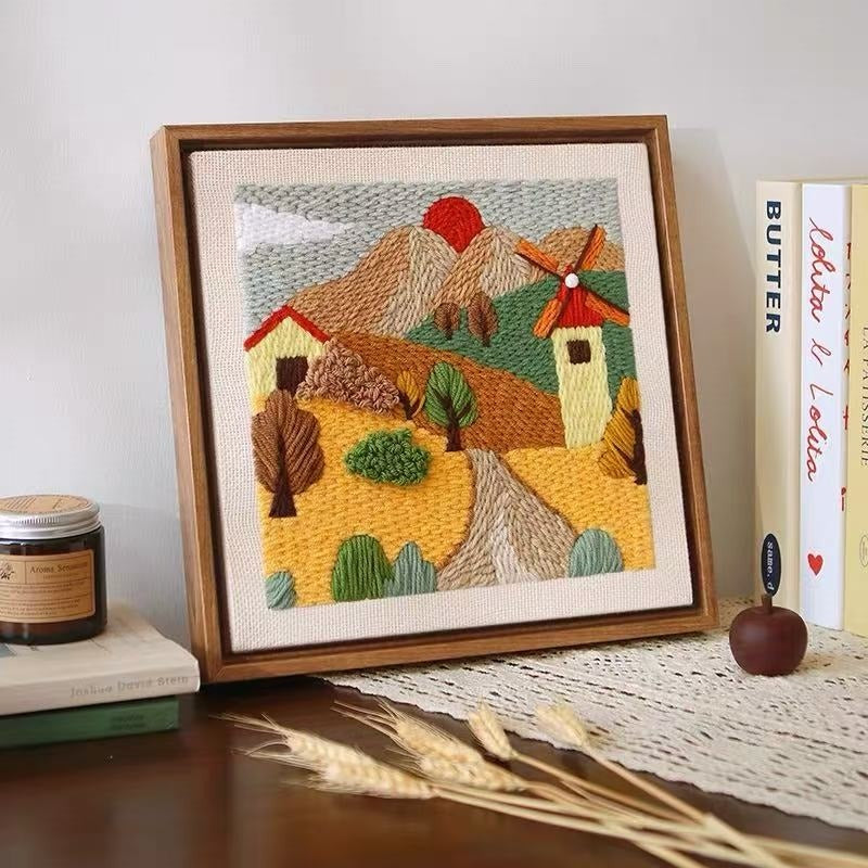 Framed yarn embroidered landscape with a windmill
