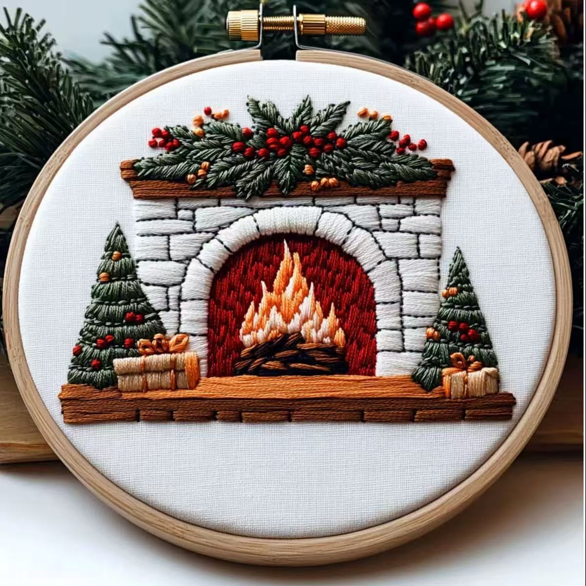 Embroidery of a fireplace scene with trees and a fire, framed in a wooden hoop.