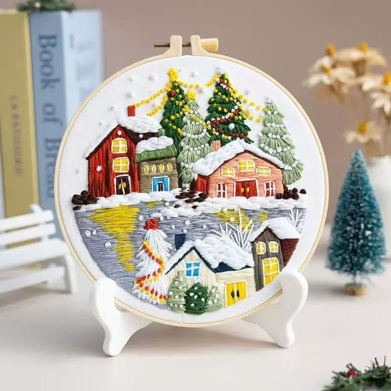 Embroidery hoop with a winter village scene on a stand