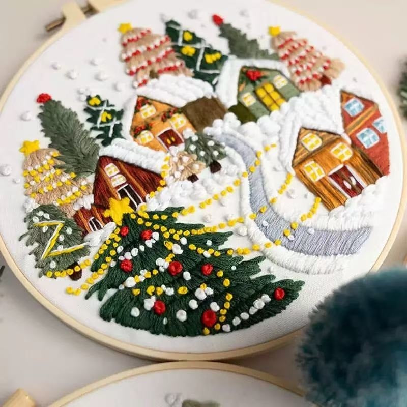 Embroidery hoop with a winter scene design featuring houses and trees.