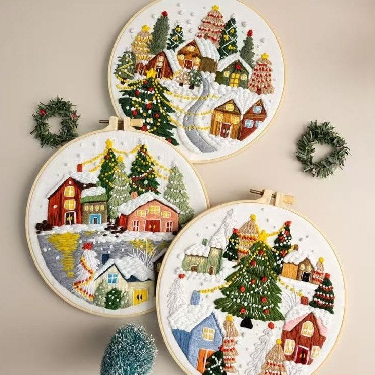 Set of four embroidered Christmas scenes with houses, trees, and wreaths on a beige background.