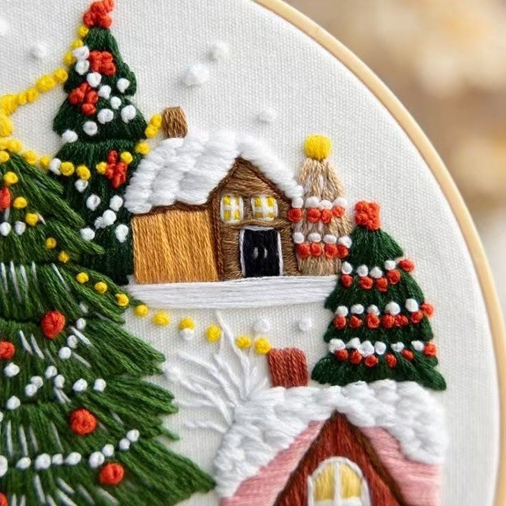Embroidery of a festive scene with trees and houses on a white background