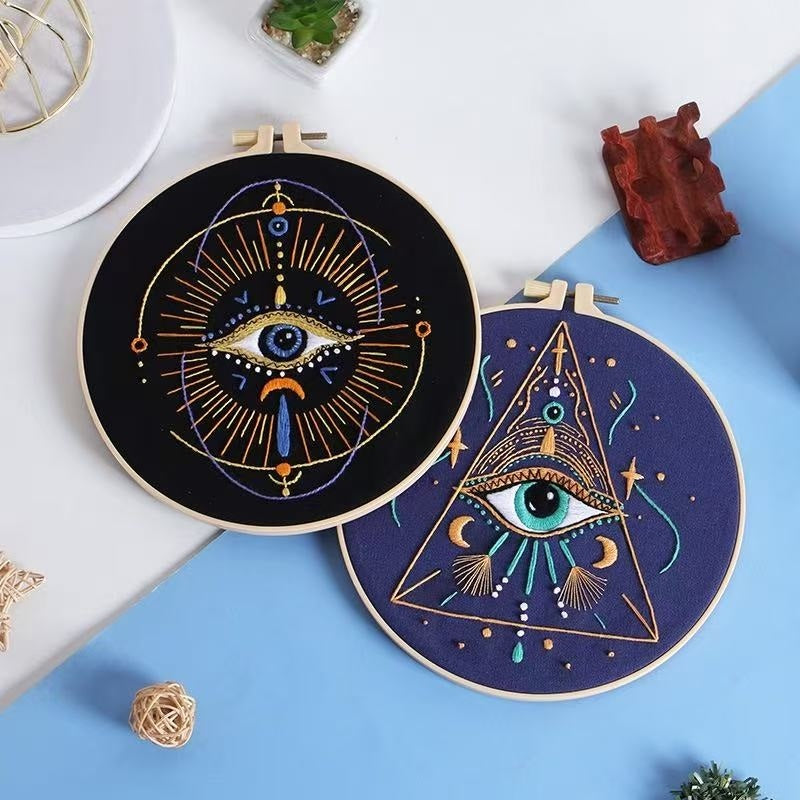 Two embroidery hoops with geometric designs on a white and blue surface.