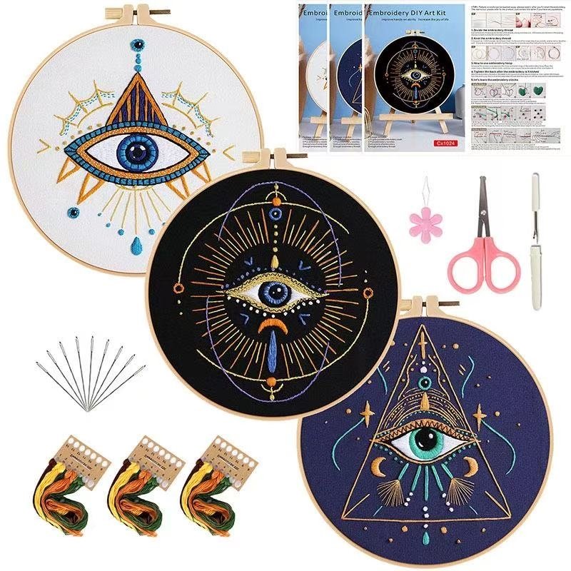 Embroidery kit with eye-themed designs on hoops, scissors, needles, and instructions.