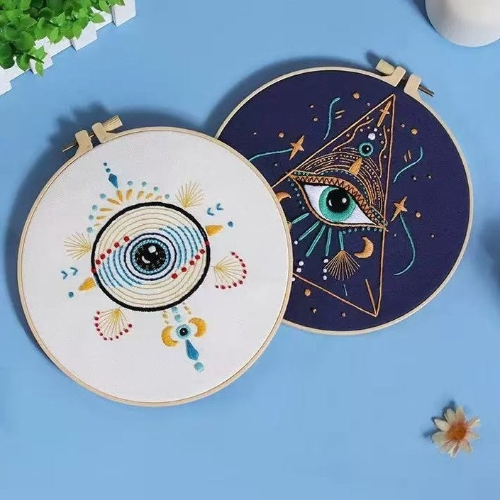 Two embroidery hoops with eye designs on a blue background