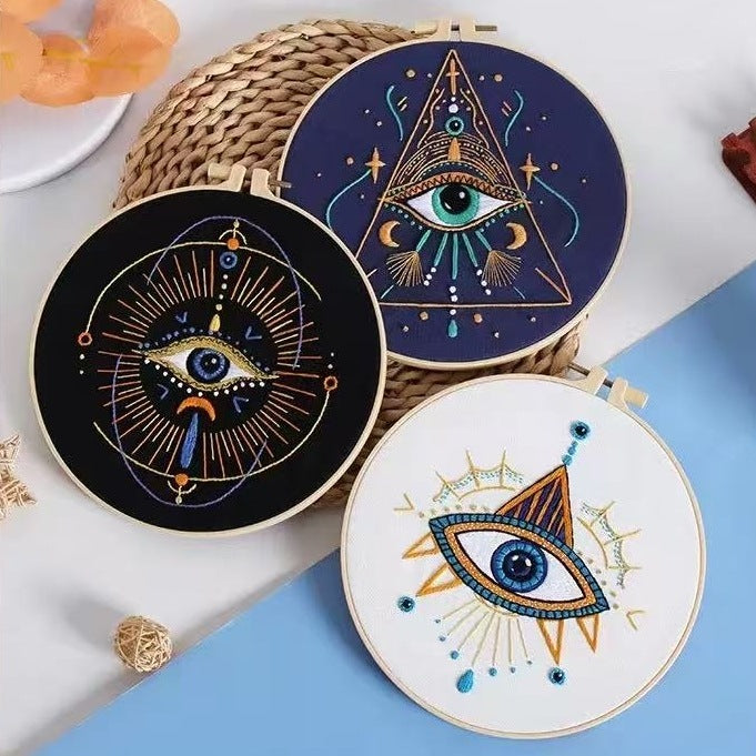 Three embroidered hoops with mystical eye designs on a white surface