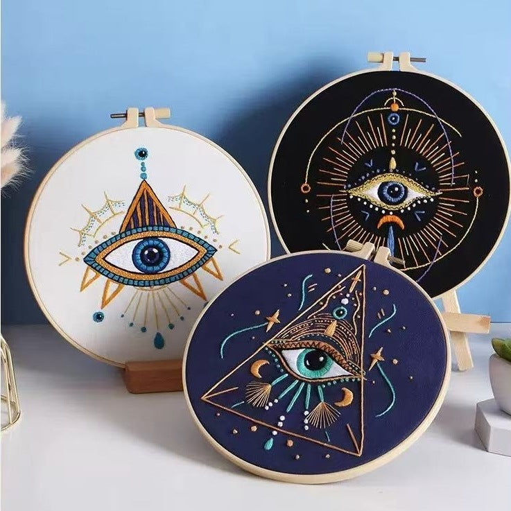 Three embroidered hoops with mystical eye designs on a light blue background