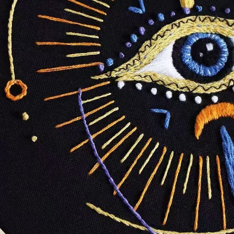 Embroidered design with an eye and geometric patterns on a black background