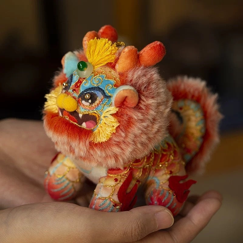 two hands holding a colorful, fluffy DIY embroidery kit in the shape of a mythical creature Kylin