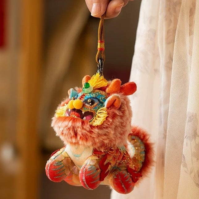 a hand holding the lanyard of a fluffy embroidered toy doll in the shape of a mythical creature Kylin