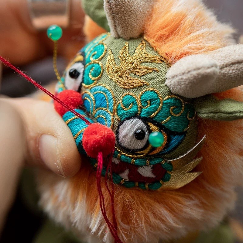a red pompom is sewn onto the face of Chinese beast Kylin with intricate designs and colors.