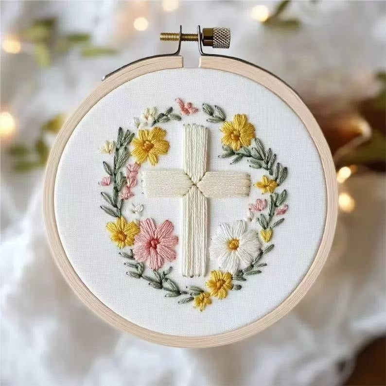 Embroidery hoop with a cross and floral design on a white background