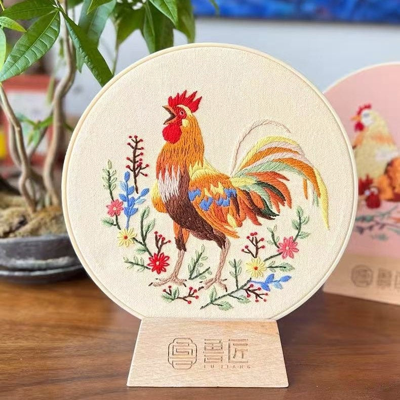 Embroidered rooster on a circular wooden stand with plants in the background
