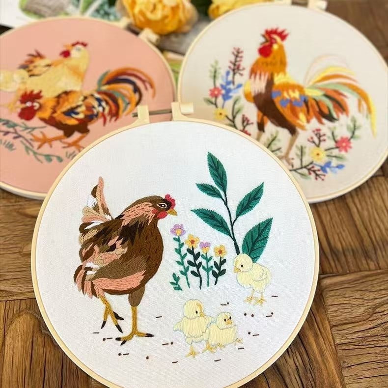 Embroidery hoop with rooster and chicken design on a wooden surface