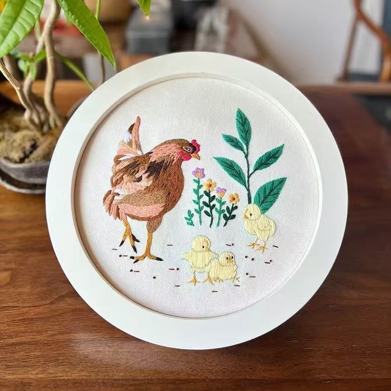 Embroidery hoop with a chicken and chicks design on a wooden surface