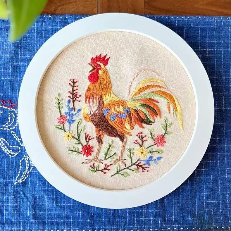 Embroidery hoop with a colorful rooster design on a blue grid background