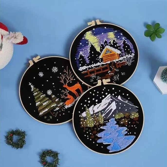 Three embroidery hoops with festive winter-themed designs on a blue background