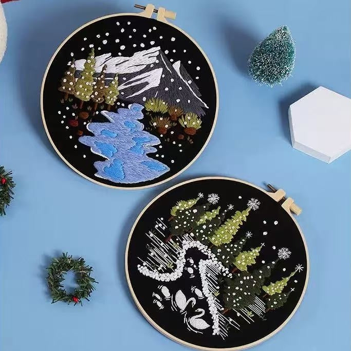 Two embroidered hoop art pieces on a blue background with Christmas-themed designs.