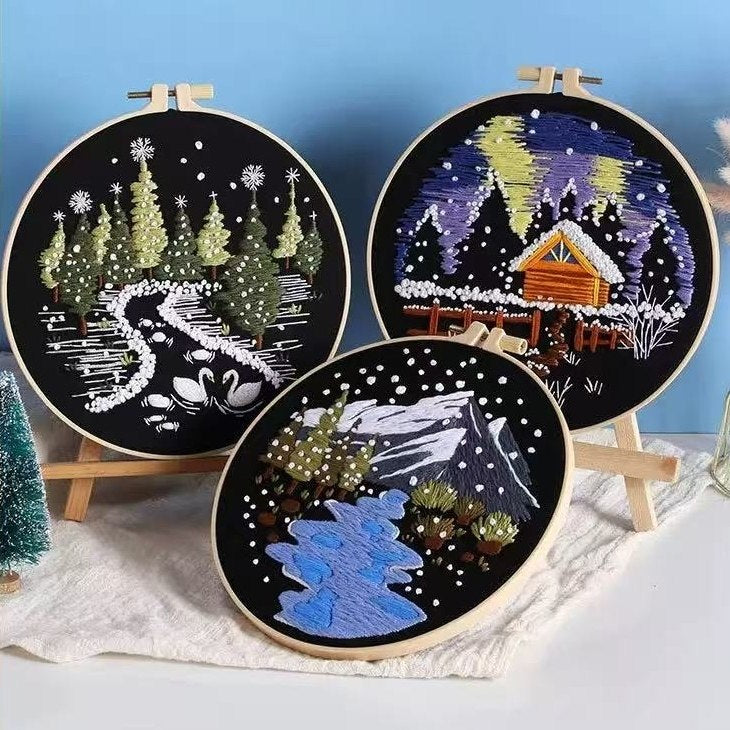Three embroidery hoops with winter-themed designs on a blue background