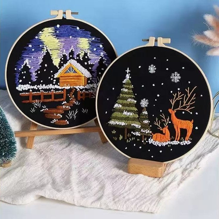 Two embroidery hoops with Christmas winter-themed designs on a white surface.