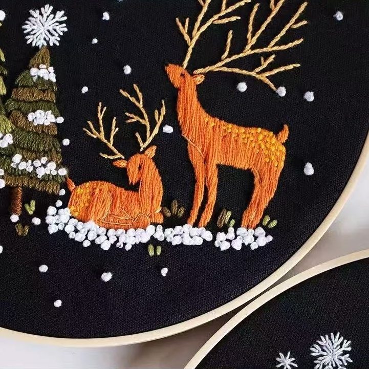 Embroidery hoop with two deer and a tree on a black background