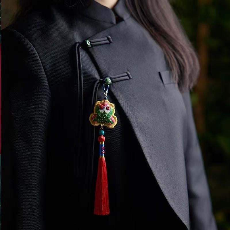 Colorful embroidered toad with a tassel pendant on a dark coat