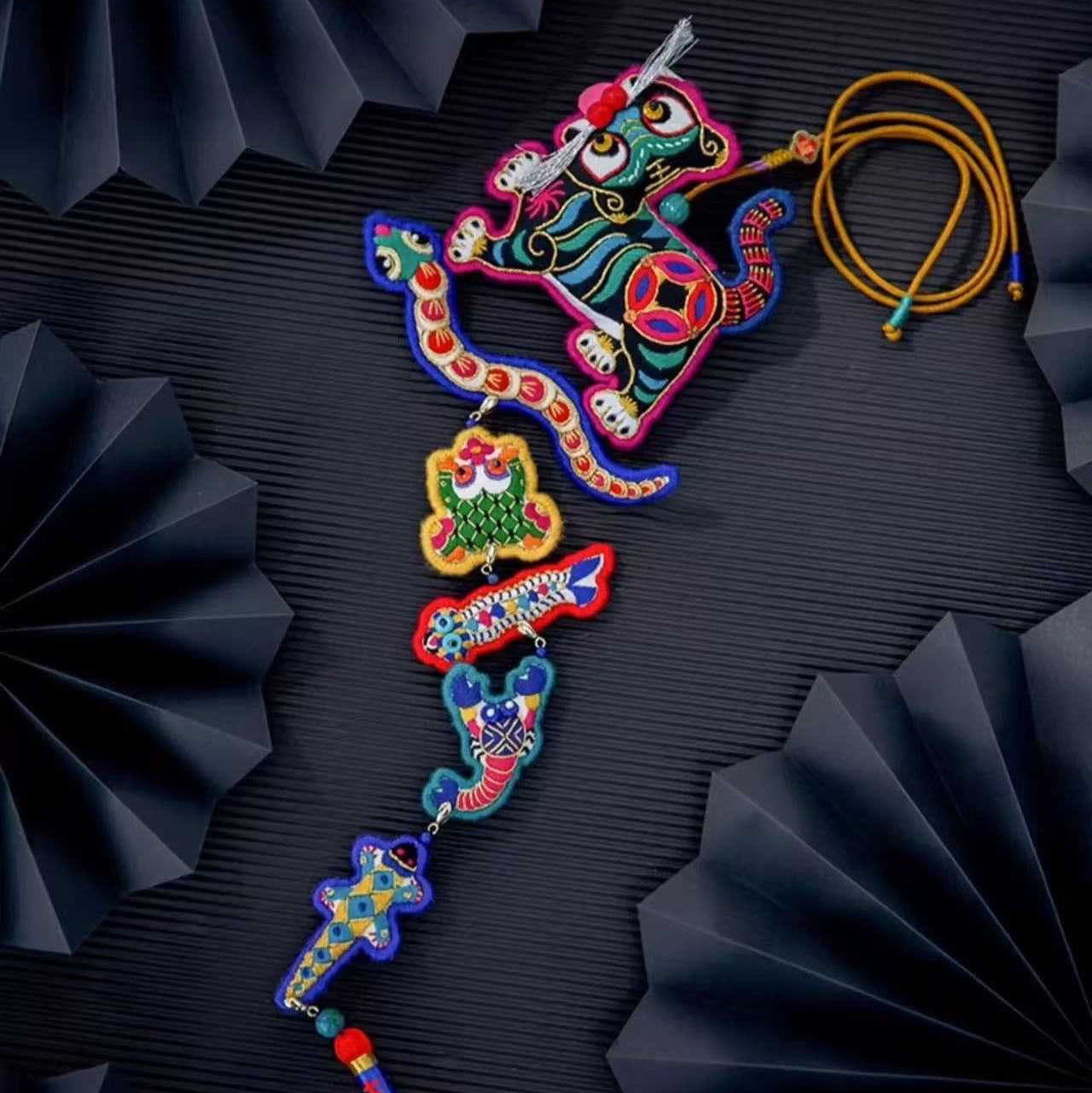 Colorful decorative embroidered tiger with five poisonous creatures with intricate designs on a black textured background