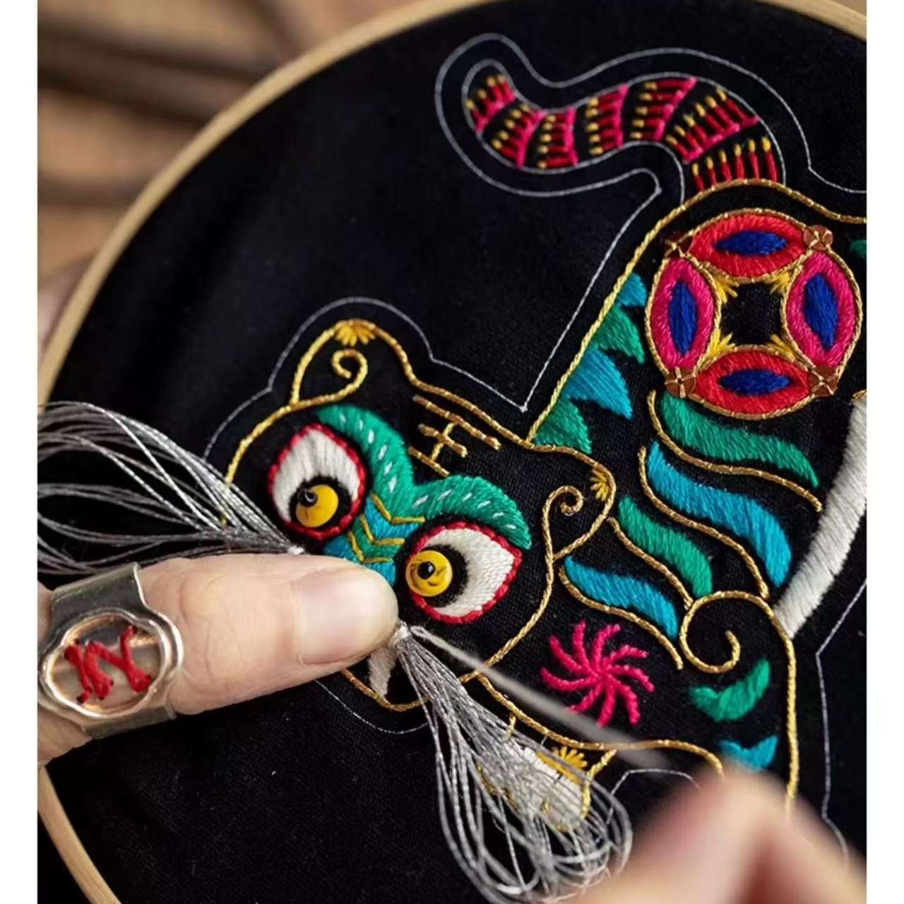 Embroidery hoop with a colorful embroidered design of a tiger.