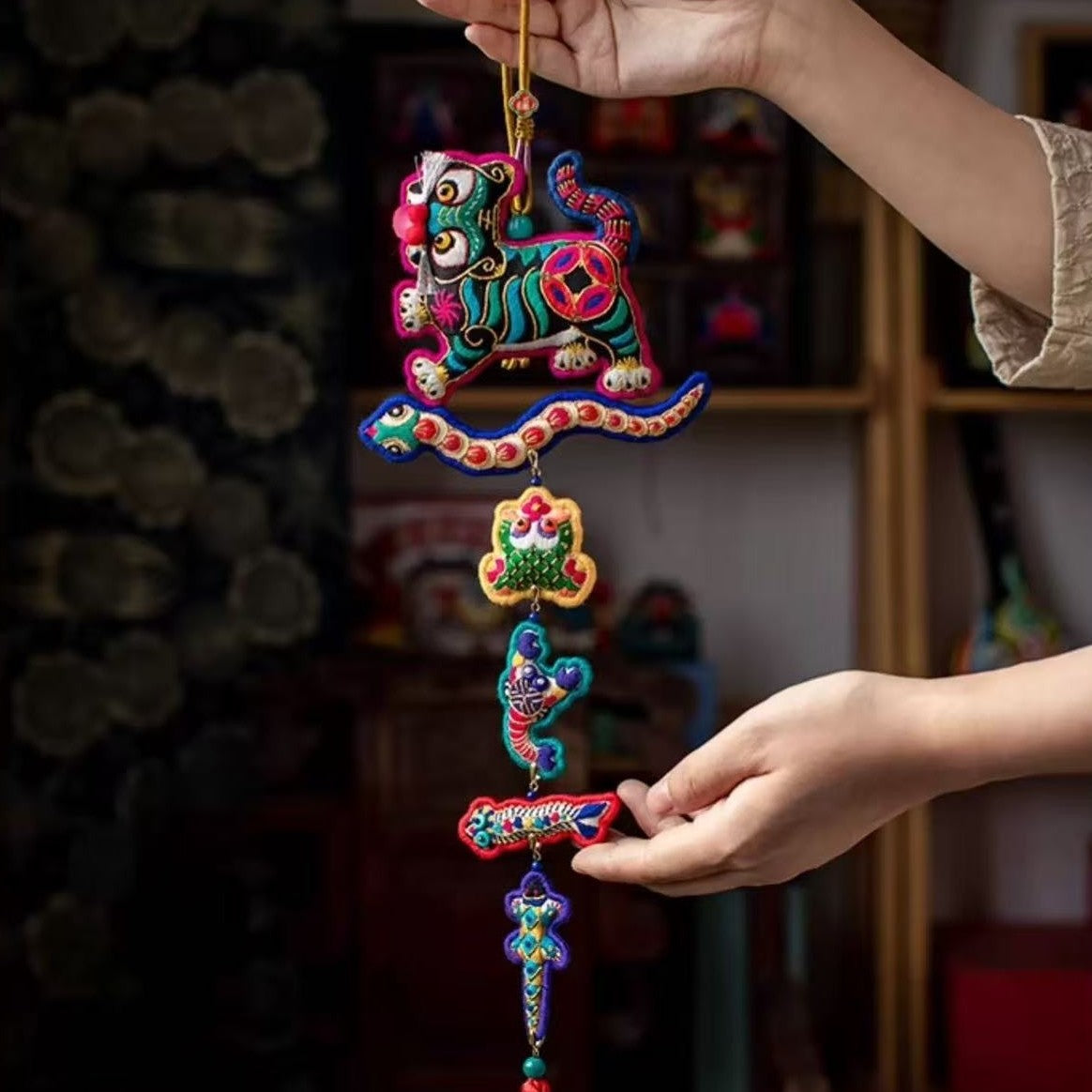 Colorful embroidered hanging decoration with tiger and five poisonous creatures held by a hand