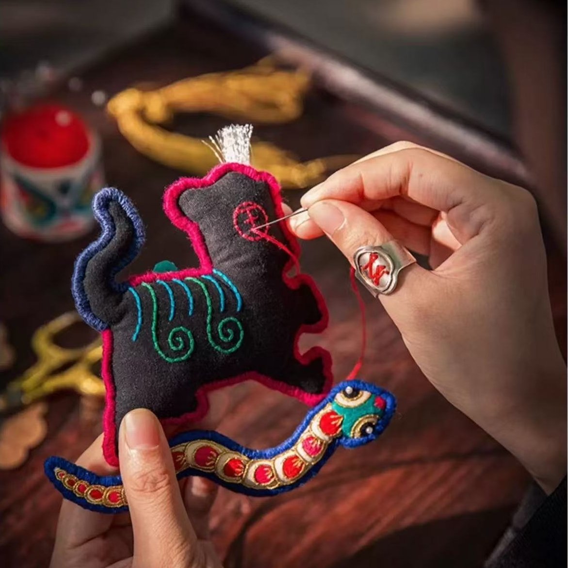 Handmade tiger and snake toy with colorful details being embroidered