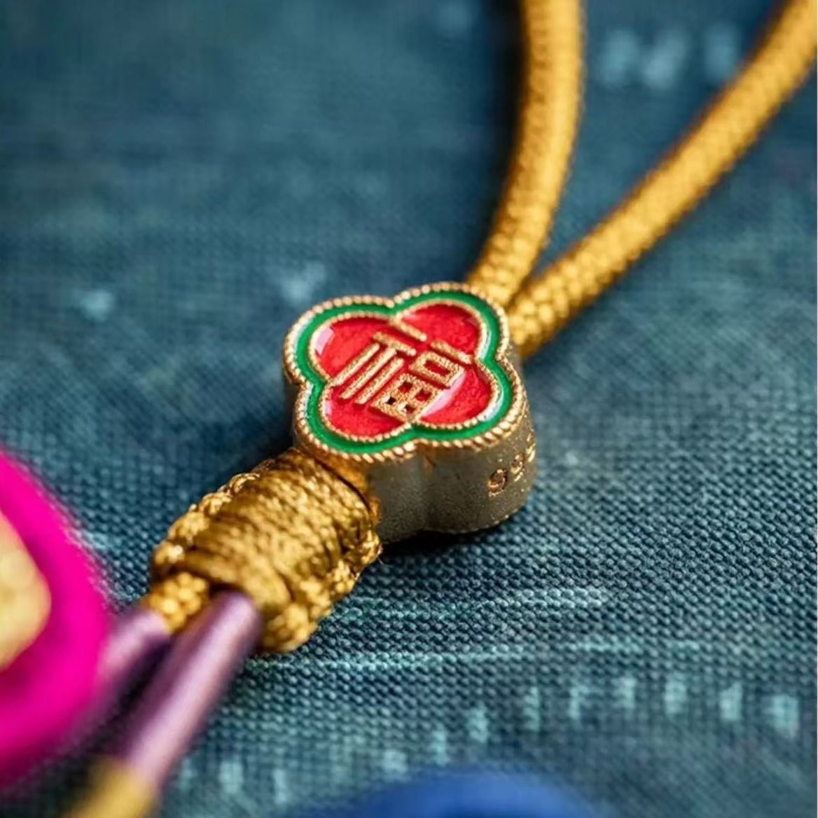 Close-up of a decorative enamel bead with intricate design on a textured fabric background