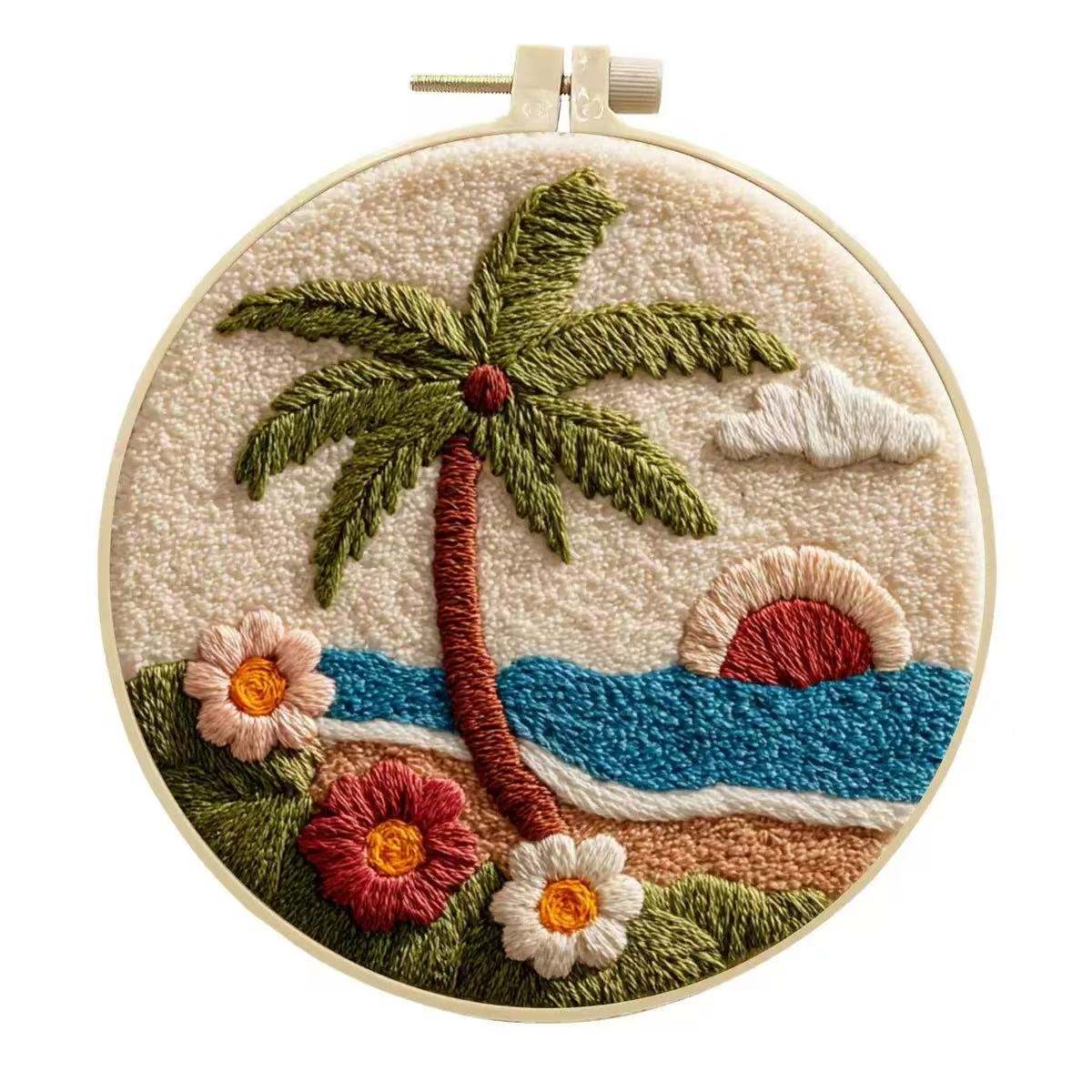 Embroidery hoop with a tropical scene including a palm tree, flowers, and sunset.