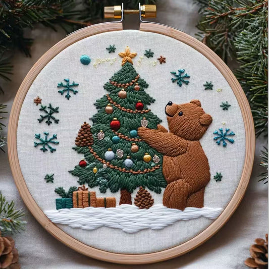 Embroidery hoop with a bear decorating a Christmas tree design.