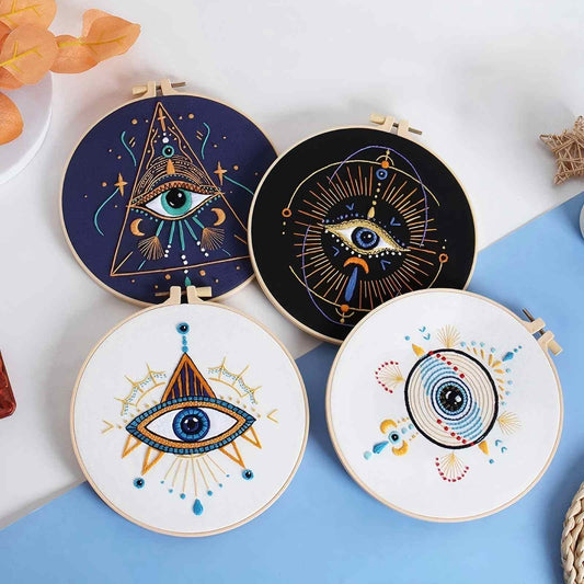 Four embroidered hoops of mystical eye designs on a white and blue background