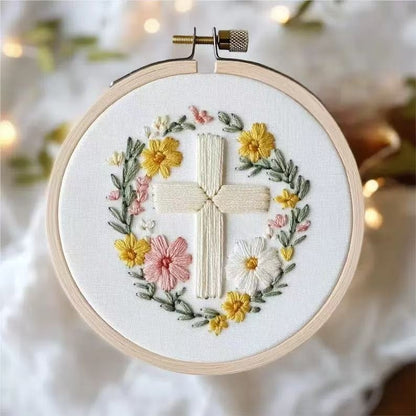 Embroidery hoop with a cross and floral design on a white background