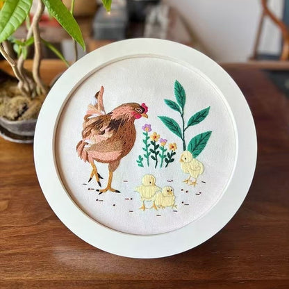 Embroidery hoop with a chicken and chicks design on a wooden surface