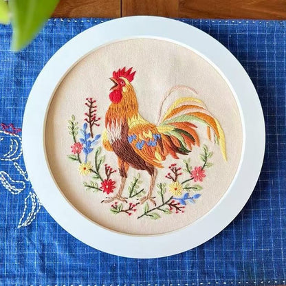 Embroidery hoop with a colorful rooster design on a blue grid background