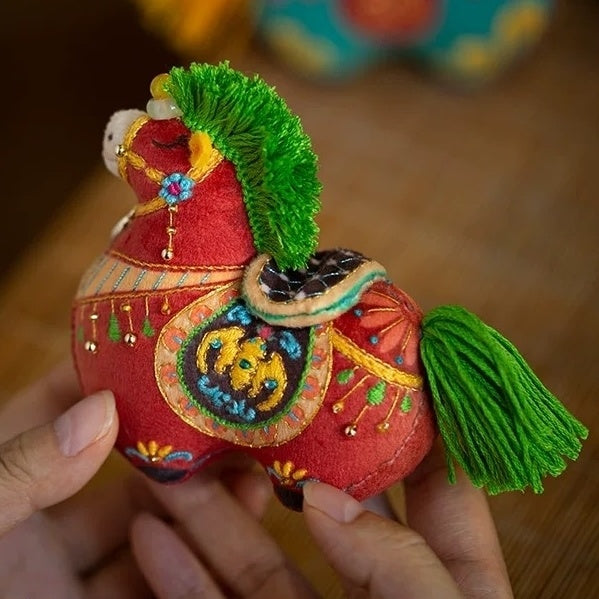 Colorful embroidered fabric horse toy held by a hand