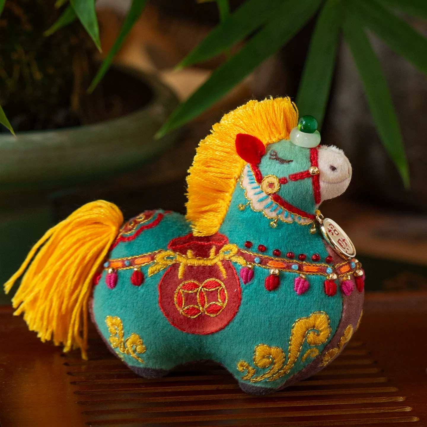 Decorative horse plush toy with colorful embroidery on a wooden surface.